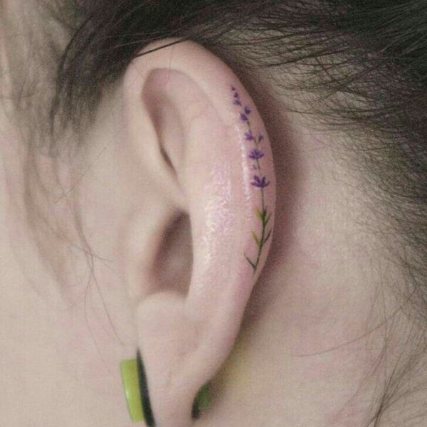 Watercolor flower tattoo on the ear.