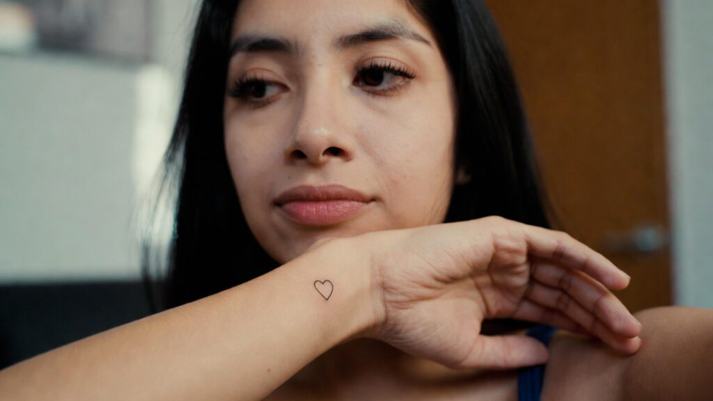 Small minimalist heart tattoo on a woman’s wrist