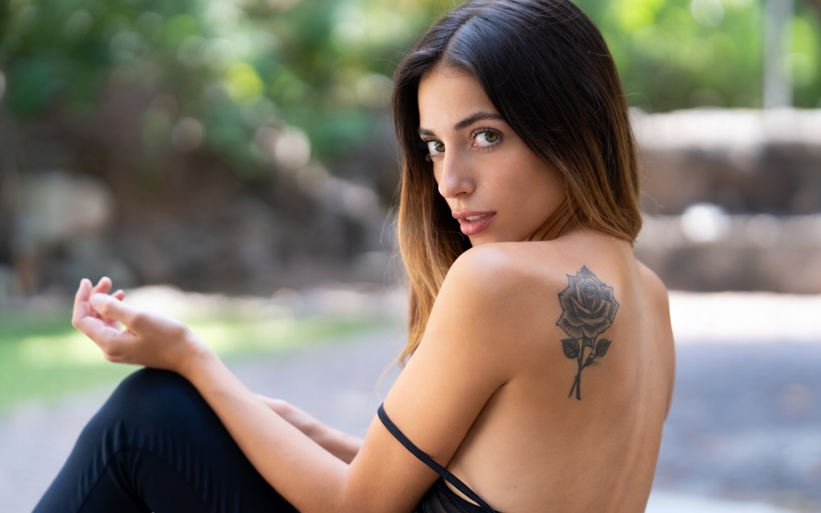 Black rose tattoo on a woman’s shoulder blade