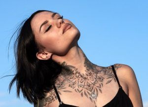Woman with tattoo on chest and collar area